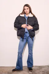 Campera puffer negra con cuello de corderito color crema, cierre frontal con cremallera y cordón ajustable en el ruedo.