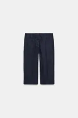 Pantalón capri de tiro medio confeccionado en denim de algodón. Presenta bolsillos de vivo en el delantero, cierre frontal con cremallera, botón y ganchos metálicos, y aberturas laterales en el bajo.