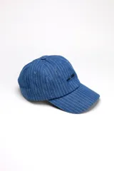 Gorra de visera curva de denim azul medio con diseño de rayas finas verticales y bordado frontal en negro.