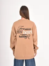 Buzo de cuello redondo en color gris oscuro, con corte holgado y mangas largas con puños elásticos. Presenta un pequeño bordado en el pecho con la palabra 'Cupid' y un corazón.