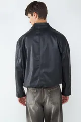 Campera de efecto cuero con cuello camisero, cierre frontal con cremallera y bolsillos laterales amplios. Presenta un diseño de corte recto y acabado liso.