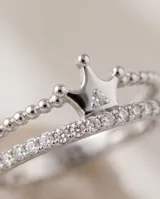 Anillo de plata 925 con diseño de corona y detalles de circonias cúbicas brillantes, acompañado por una alianza fina decorada con pequeñas piedras incrustadas.