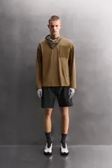 Camiseta de algodón de corte relajado (relaxed fit), color verde oliva, con cuello redondo, manga larga y bolsillo plastrón con cierre de cremallera en el pecho.