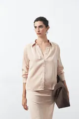 Camisa negra de corte relajado y caída fluida, con cuello clásico, escote en V y cierre frontal con botones forrados. Presenta mangas largas con puños abotonados.