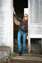 Campera de lana italiana con diseño de motivos tribales en tonos oscuros, rojos y beige. Presenta cierre frontal, bolsillos laterales y detalle de flecos largos de gamuza en las mangas.