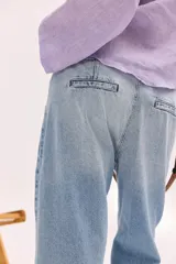Pantalón de jean de tiro bajo y calce relajado, con cierre frontal de múltiples botones visibles y largo al tobillo.