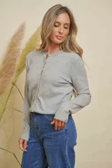 Saco de punto color gris claro, con cuello redondo y cierre frontal de botones. El cuello está decorado con detalles de strass.