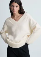 Jersey de punto medio con cuello en pico y diseño oversize. Presenta mangas largas y terminaciones de canalé en cuello, puños y ruedo.