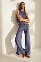 Pantalón azul marino de corte wide leg con detalles en tono marrón tostado en la cintura, bolsillos y bordes laterales, cuenta con trabillas para cinturón y cierre frontal.