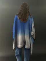 Ruana azul con degradé a gris, confeccionada en lana merino fina y suave, teñida artesanalmente. Presenta cuello plisado en fieltro de lana merino.