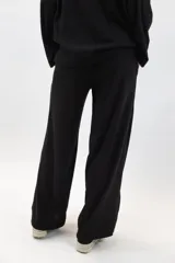 Pantalón negro de tejido acanalado, de corte amplio y tiro alto, con bolsillos laterales.