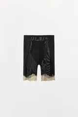 Shorts de tiro alto, color negro, confeccionado en tejido semitransparente de poliamida. La cintura es elástica y el bajo está rematado con una aplicación de encaje en tono beige/dorado.