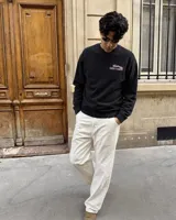 Buzo negro de cuello redondo y manga larga, de corte regular fit. En la espalda presenta un estampado gráfico en color blanco y rosa con la leyenda "Fletes" y el dibujo de una grúa transportando una planta.