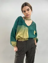 Pantalón tipo babucha de lana de oveja, color negro, con cintura alta, piernas rectas y amplias, y detalle de textura vertical en el frente. Presenta puños ajustables con elástico y broches en la parte inferior.