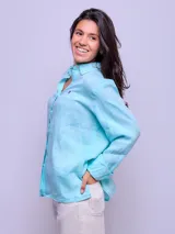 Camisa de lino color celeste, de manga larga, con cierre frontal de botones y cuello camisero.