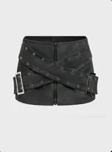 Minifalda negra de cuero sintético con cierre frontal con cremallera y cintas cruzadas con hebillas metálicas.