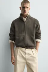 Chaqueta relaxed fit de punto tejido en hilatura con mezcla de algodón, color beige, con cuello subido y manga larga. Cuenta con acabados en rib, efecto lavado y cierre frontal con cremallera.