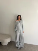 Conjunto gris melange compuesto por un buzo de cuello bote amplio y mangas largas, y un pantalón largo de corte ancho y holgado.
