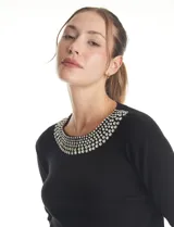 Buzo de tejido fino color beige, con cuello redondo decorado con apliques de brillos y mangas largas.