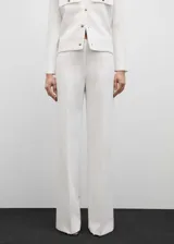 Pantalon de vestir de corte recto y diseño largo, confeccionado en tejido fluido de color blanco. Cuenta con dos bolsillos laterales y cierre oculto de botón, gancho y cremallera.
