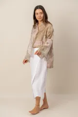 Camisa beige de manga larga con estampado botánico y floral, confeccionada en tejido liviano y traslúcido, con cuello camisero y cierre frontal de botones.