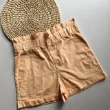 Short color amarillo pastel con cintura elastizada y detalle de botones frontales.