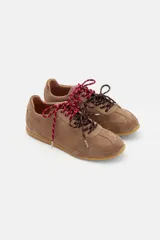 Zapatilla de cuero marrón con paneles de gamuza y cuero liso, suela de goma color caramelo y cordones bicolores en rosa y blanco.