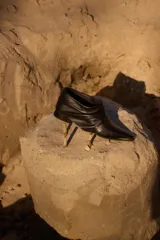 Botineta de gamuza azul marino con diseño drapeado, punta fina con puntera metálica y placa metálica decorativa en el lateral. Posee taco bajo cuadrado.