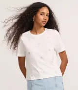 Remera blanca de algodón con cuello redondo y manga corta, con pequeños corazones bordados distribuidos por toda la prenda.