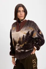 Buzo de tejido de punto jacquard con textura de pelo, con diseño estampado de paisaje de bosque. Presenta cuello alto con cierre frontal parcial, puños acanalados en tonos marrón y crema, y un parche decorativo en la manga.