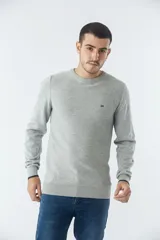 Sweater de punto con textura geométrica, color gris, de cuello redondo y manga larga. Presenta puños y ruedo acanalados con detalle de borde en color oscuro y logo bordado en el pecho.