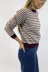 Buzo de punto fino con diseño de rayas horizontales en negro y blanco, cuello redondo, mangas largas y puños y ruedo en tono liso.