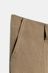 Pantalón de tiro medio confeccionado en tejido fluido color tostado. Presenta bolsillos de plastrón en el delantero y en la pierna, solapas en la espalda y detalle de frunces ajustables en el bajo. Cierre frontal con cremallera y botón.
