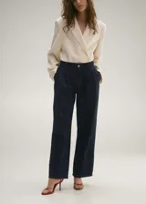 Pantalón de jean estilo wideleg en color azul oscuro. Presenta un diseño de tiro medio con cierre frontal de cremallera y botón, detalle de pinzas en la cintura, trabillas para cinturón y dos bolsillos laterales.