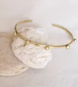 Pulsera rígida de bronce color dorado con bolitas decorativas.