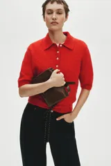 Remera polo de manga corta confeccionada en punto suave con mezcla de mohair y lana, color rojo, con cuello clásico, tapeta con botones frontales y ribetes acanalados.