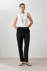 Pantalón de corte recto en color beige, con cintura media y cierre frontal oculto. Presenta un diseño limpio y minimalista con bolsillos laterales.