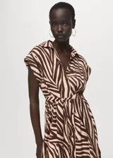 Vestido midi de corte recto con estampado animal print tipo cebra en tonos marrón y beige. Presenta cuello camisero, cierre frontal con botones, mangas cortas con vuelta y cinturón tipo batín para ajustar a la cintura.