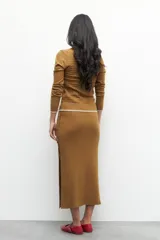 Falda larga marrón de punto con elástico en la cintura y botones decorativos en un lateral.