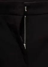 Pantalón de vestir negro, de corte ajustado y tobillero, con cierre frontal de cremallera y botón, trabillas para cinturón y bolsillos de ribete traseros.