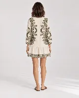 Vestido corto de color beige con diseño estampado en tono verde militar, escote en V con cordones y borlas colgantes, mangas largas y volado en el ruedo.