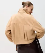 Campera de gamuza sintética color tostado con botones dorados grabados, cuello camisero, bolsillos frontales aplicados y mangas largas con puños abotonados.