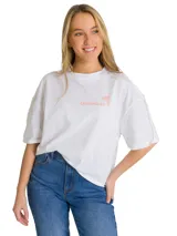 Remera blanca de corte oversize con cuello redondo y mangas cortas. Presenta un estampado gráfico en el pecho con el logo de la marca y una palmera en color salmón.
