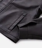 Campera de estilo urbano confeccionada en poliuretano con acabado lavado y textura que imita el cuero. Presenta cuello inglés, cierre frontal con cremallera, vista con botones y bolsillos delanteros amplios.