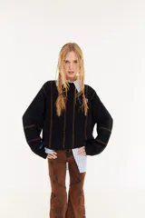 Sweater de punto color beige, con diseño de textura acanalada en mangas y espalda, cuello polo en color bordó y parche decorativo en la parte superior de la espalda.