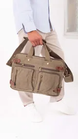 Mochila porta notebook color verde oliva de tela canvas con detalles en cuero marrón. Tiene múltiples bolsillos con cierre y correas ajustables.