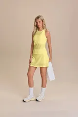Conjunto deportivo de musculosa y pollera color amarillo, confeccionado en tejido texturizado microperforado. La musculosa presenta diseño sin mangas y calce ajustado, mientras que la pollera incluye un short interior.