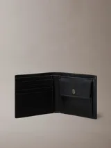 Billetera bifold Calvin Klein confeccionada en piel con textura saffiano. Cuenta con compartimento para billetes, múltiples ranuras para tarjetas y monedero interno. Presenta logo metálico de la marca en el frente.