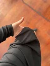 Vestido midi negro de corte ajustado, cuello alto y mangas largas. Presenta una abertura lateral en la falda y largo asimétrico.