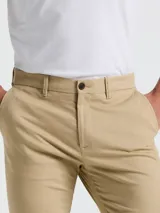 Pantalón chino color beige, con bolsillos delanteros diagonales, cierre y botón en la cintura. Logo bordado a tono.